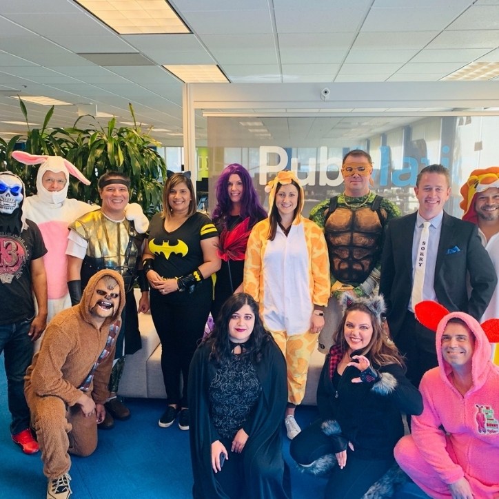 Thirteen smiling PubMatic employees dressed up in costumes