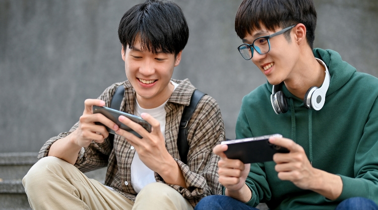 Two men playing mobile game together smiling