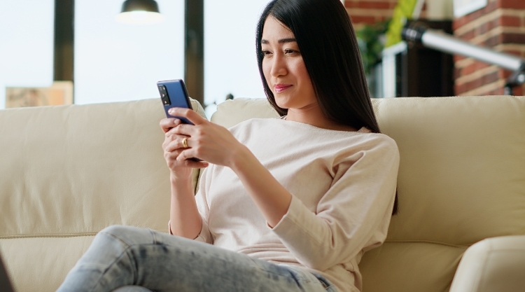A woman uses her mobile device while sitting on the couch