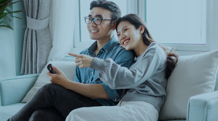 Japanese couple sitting on couch watching TV